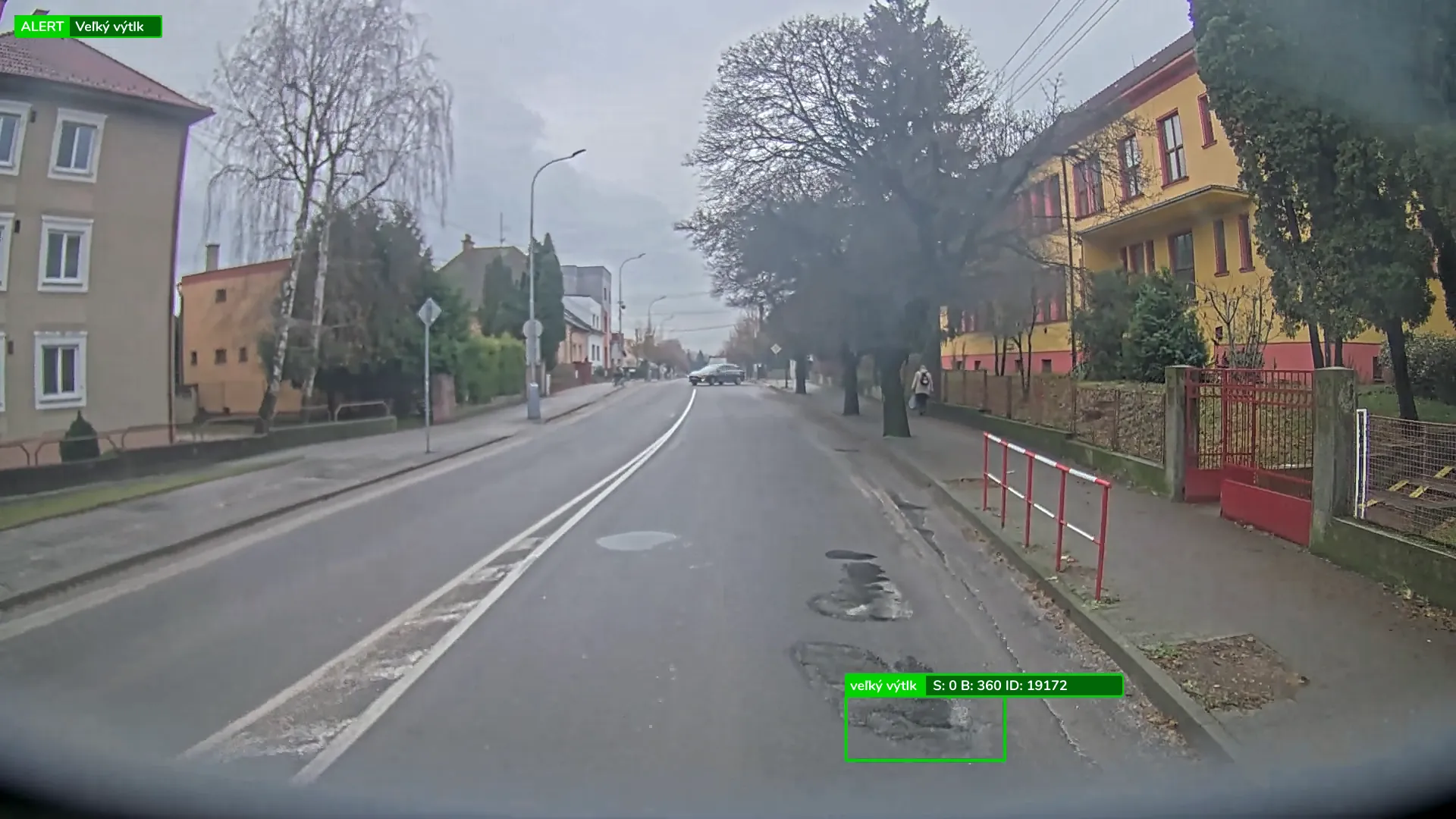 A town street seen from a collection vehicle’s camera, with the console’s alert on a large pothole in the lane