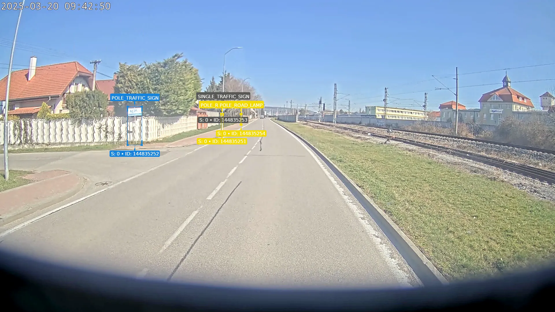A vehicle’s camera on a street by the railway, the trees, street lamps, traffic signs and graffiti labelled by the CAMAN console as they pass